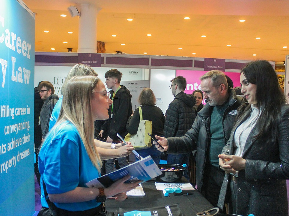 An employer and candidate in conversation at a recruitment stand at the Manchester Job Show